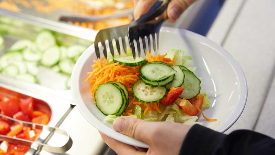 An einem Salatbuffet wird ein Teller befüllt