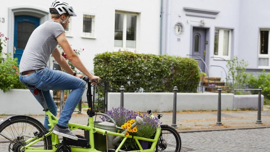 Ein Mann fährt auf einem Lastenrad.