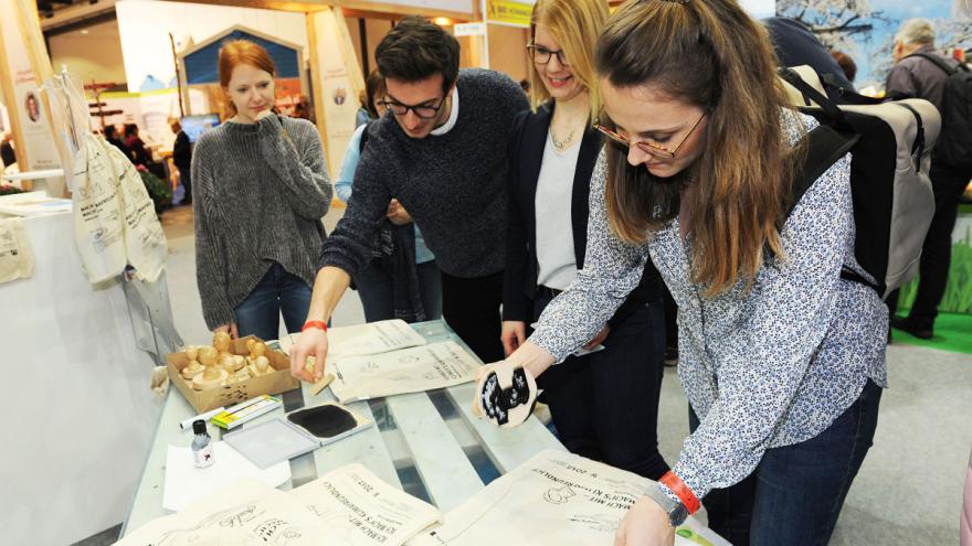 Mehrere Personen bestempeln Baumwolltaschen an einem Messestand
