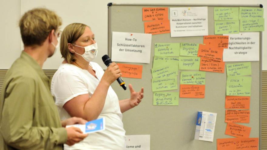 Workshop: Moderator und Moderatorin stehen vor einer Metaplanwand mit Ergebnissen
