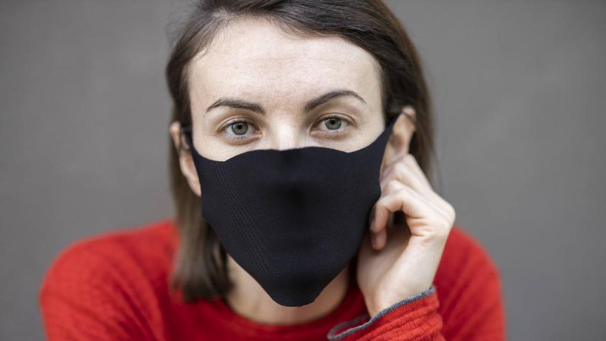 Eine junge Frau trägt einen schwarzen Mund-Nasen-Schutz