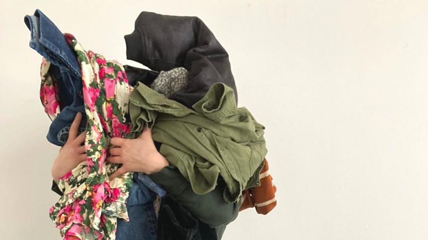 Eine Person hält viele Kleidungsstücke, nur die Hände sind zu sehen