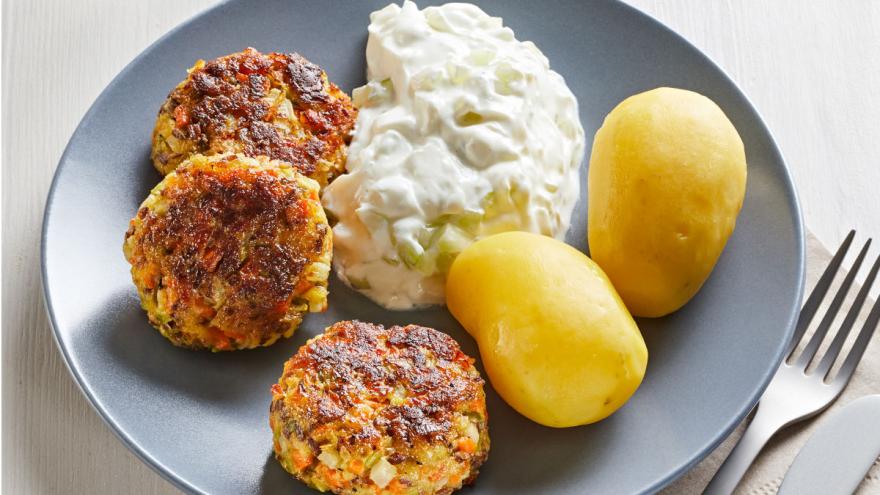 Gemüsefrikadellen mit Tzatziki und Pellkartoffeln auf einem Teller