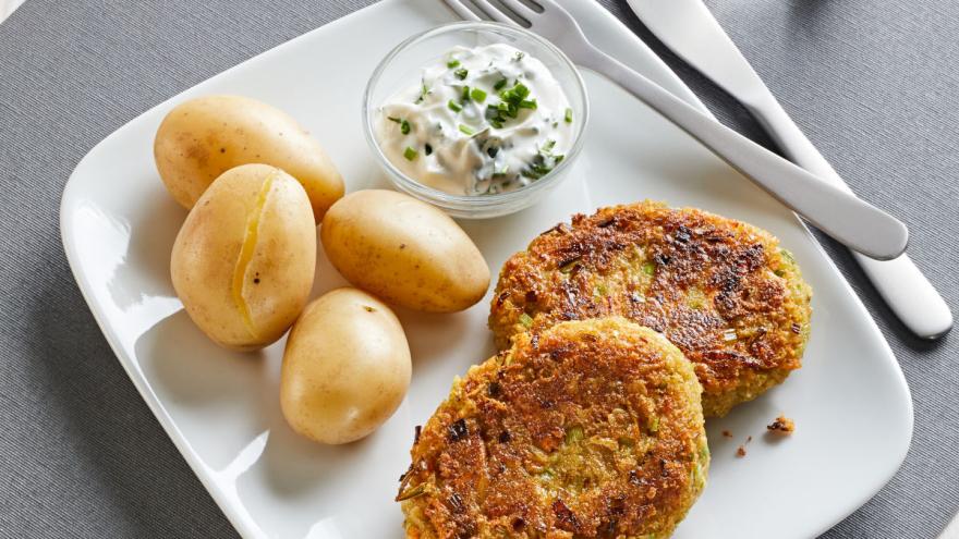 Grünkernbratlinge mit Pellkartoffeln und Kräuter-Joghurt-Soße auf einem Teller