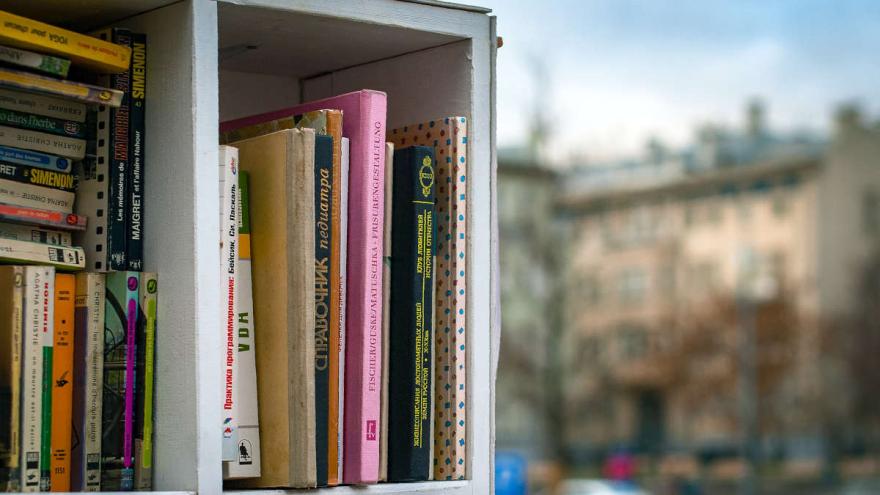 Offener Bücherschrank mit Häusern im Hintergrund