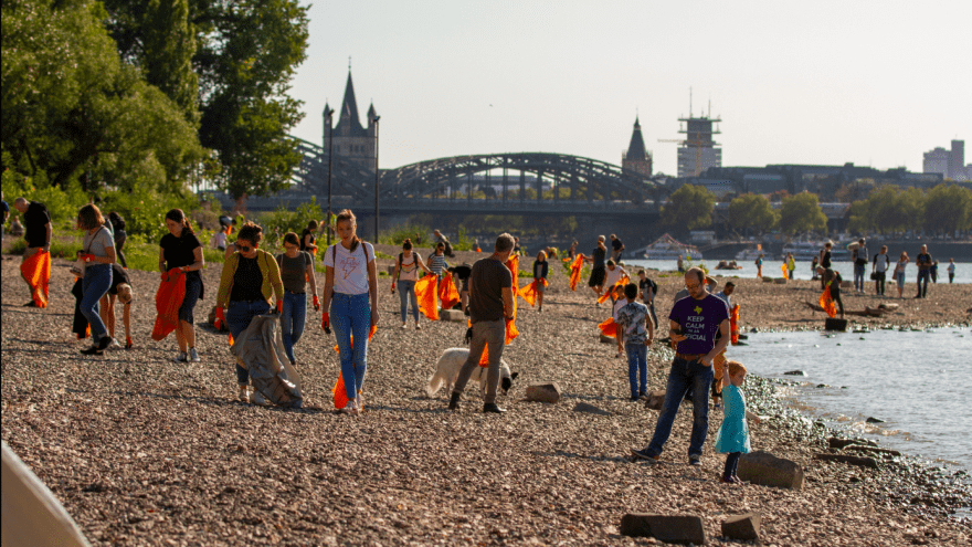 Viele Personen sammeln gemeinsam Müll am Rhein.