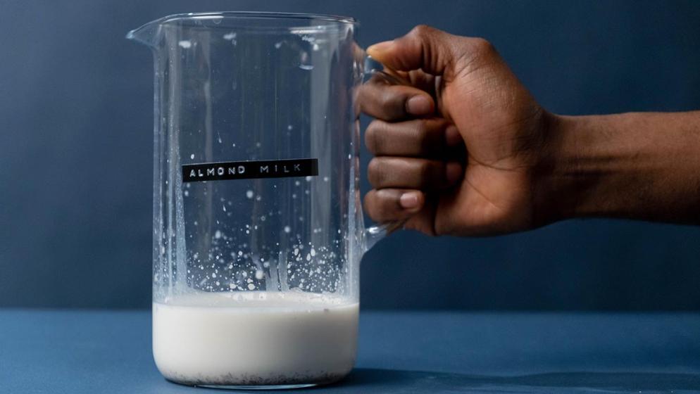 Eine Hand hält einen Glaskrug mit Mandelmilch