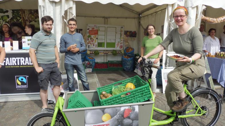 Eine Frau fährt mit dem beladenen Lastenrad an den Ständen vorbei
