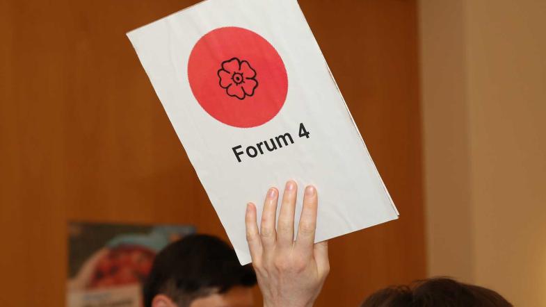 Ein Schild "Forum 4" wird hochgehalten.