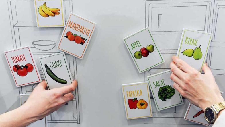 Hände sortieren Karten, auf denen Obst- und gemüsesorten abgebildet sind.