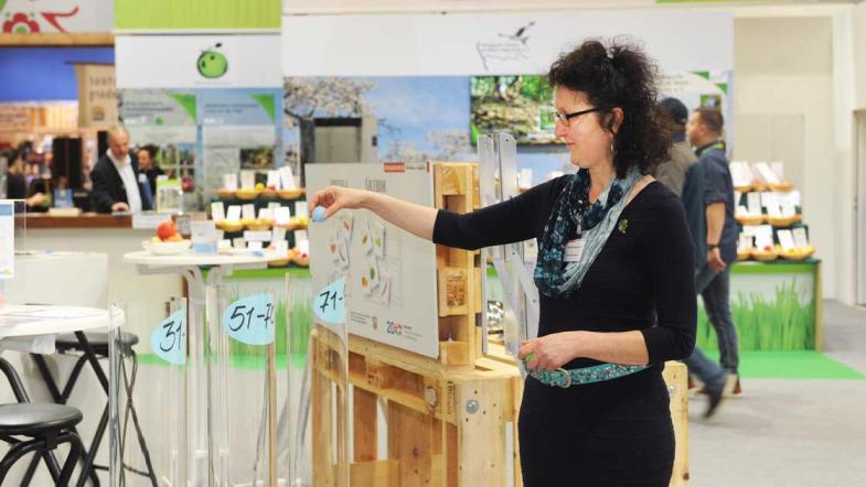 Eine Frau am MehrWert-Stand wirft einen Ball in eine Rohre (Spiel)