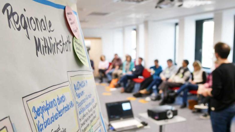Ein Flipchart, ein Redner und Publikum
