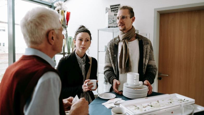 Drei Personen unterhalten sich bei einer Tasse Heißgetränk