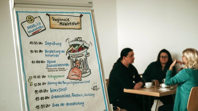 Drei Personen unterhalten sich an einem Tisch sitzend
