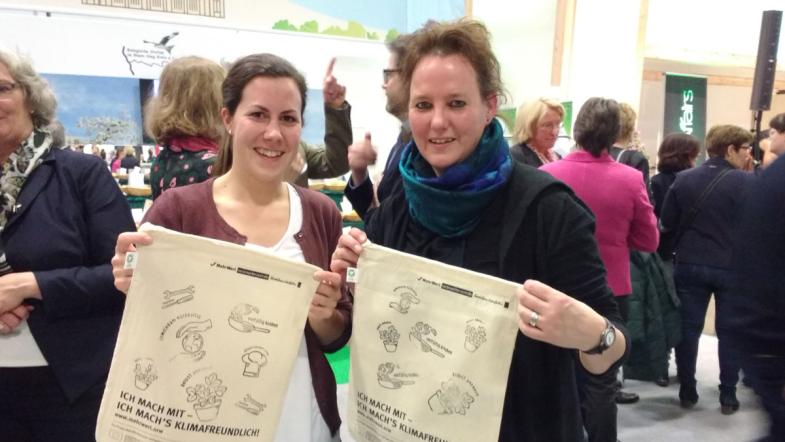 Zwei Frauen halten bedruckte Baumwolltaschen in die Kamera