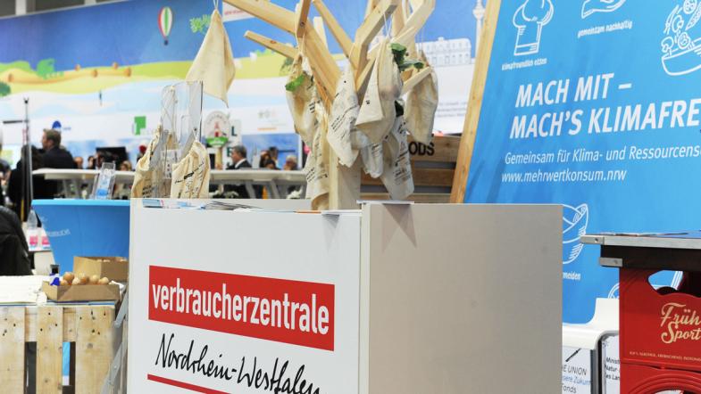 Der Messestand von MehrWert, an einem Holzbaum hängen Baumwollbeutel