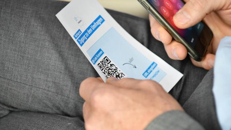 Eine Person scannt mit einem Handy einen QR-Code ein