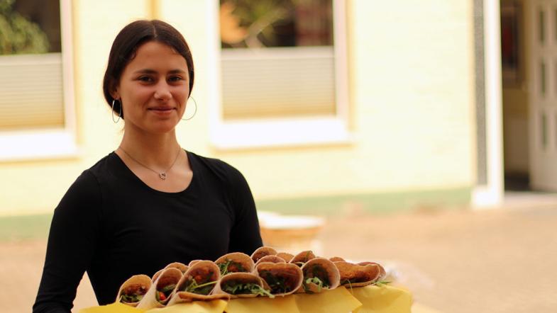 Ein Mädchen hält ein Tablett mit Wraps.