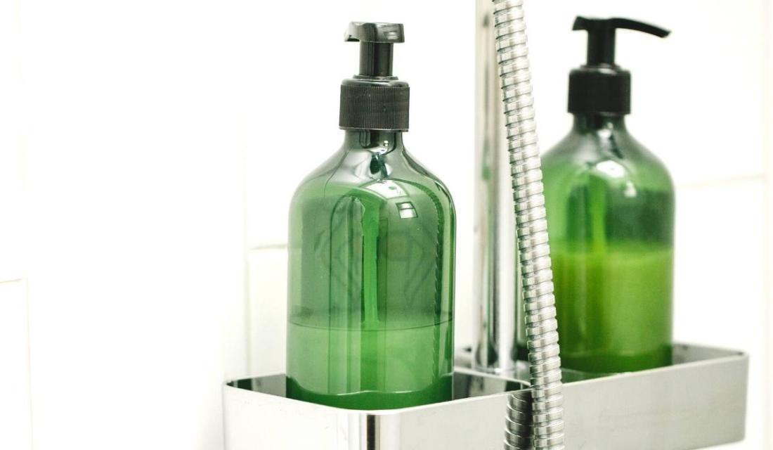 Zwei grüne Flaschen Duschgel in einer Dusche